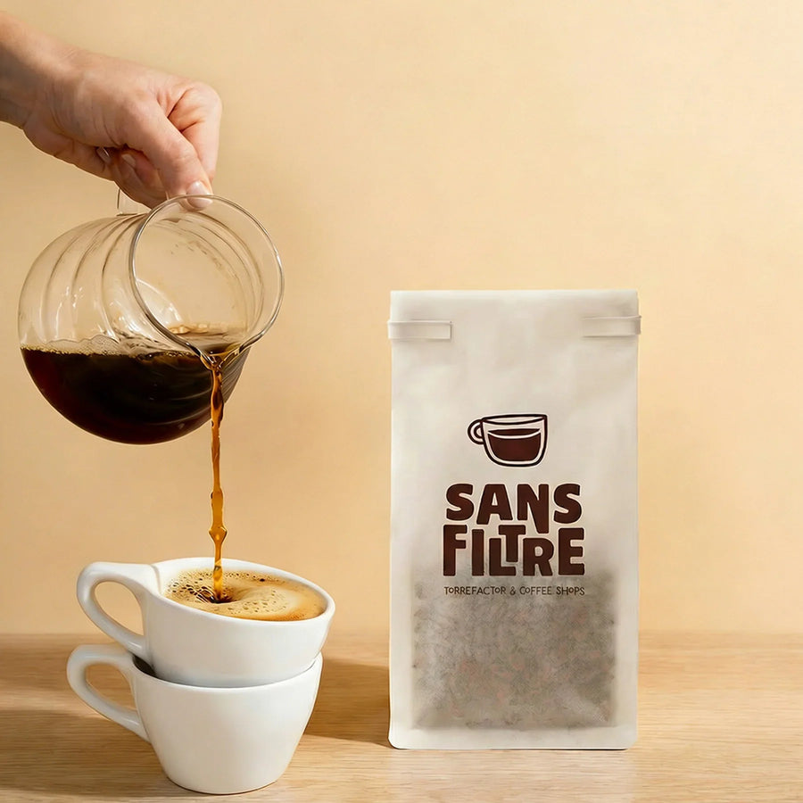 Coffee is being poured into a cup next to a tissue paper bag of coffee.