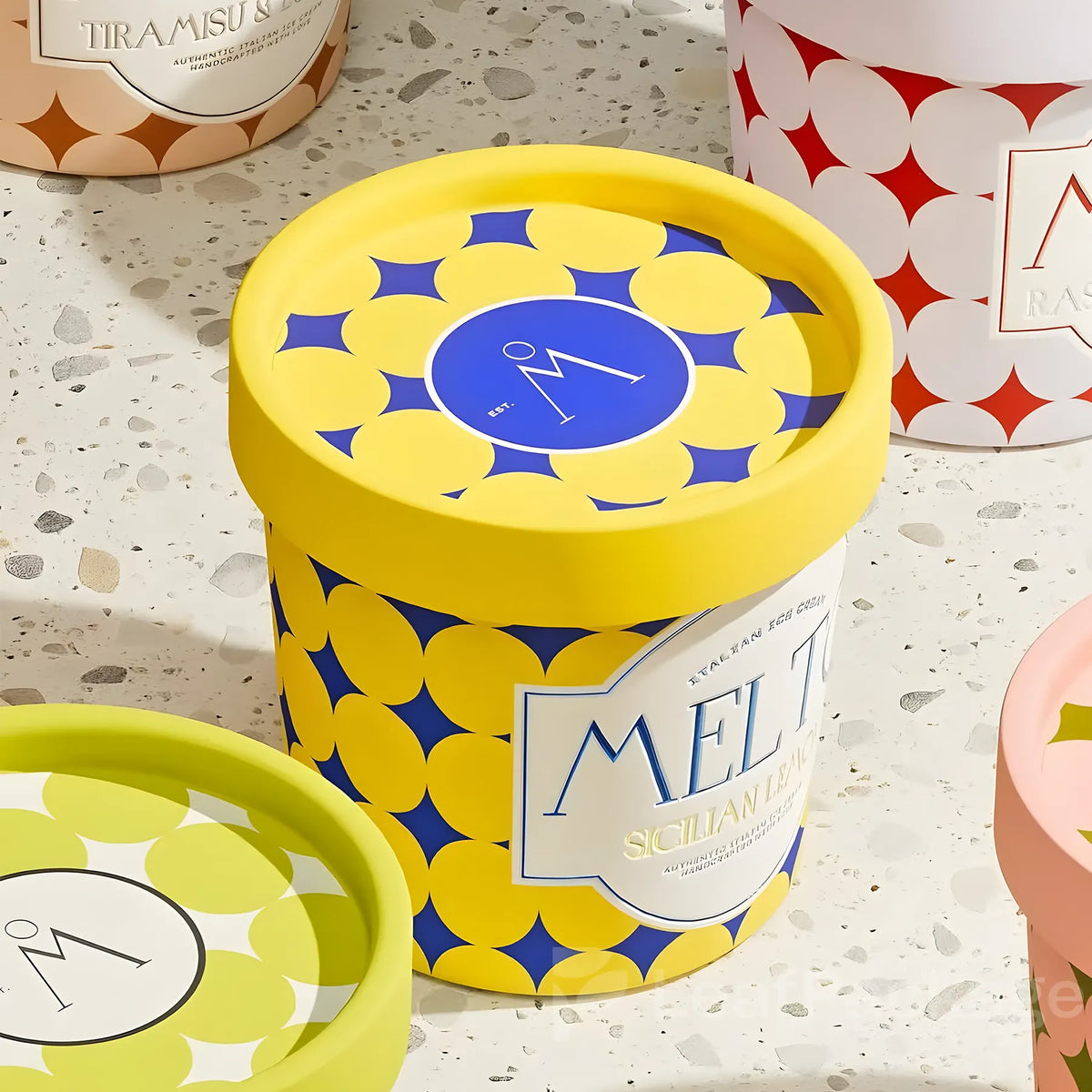 Yellow and blue ice cream container sitting on a counter surrounded by four other ice cream containers.
